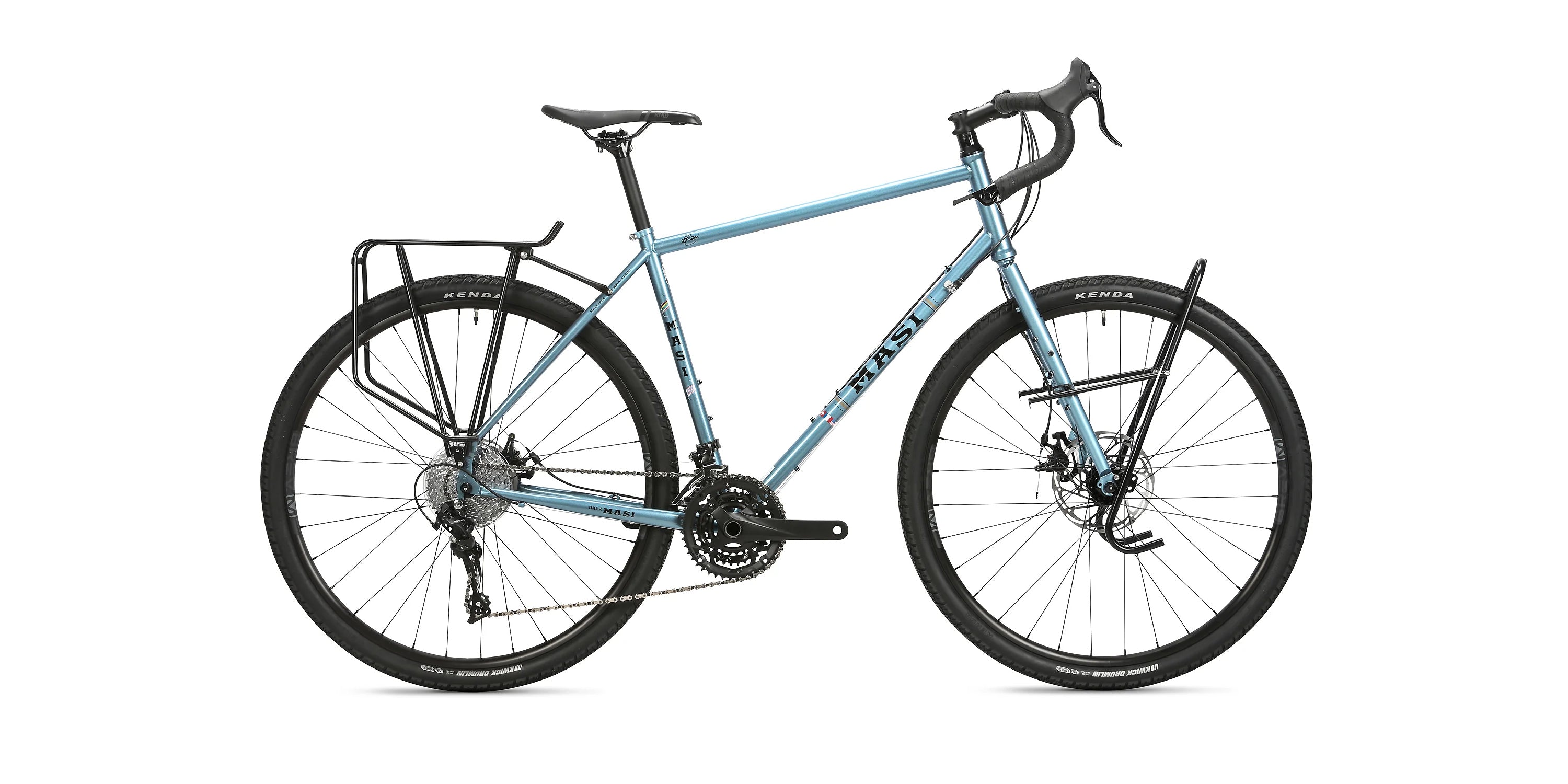 Side view of a light blue touring bicycle with drop handlebars and a rear storage rack. The bike features a black seat, disc brakes, and Kenda tires on black wheels, set against a plain white background.