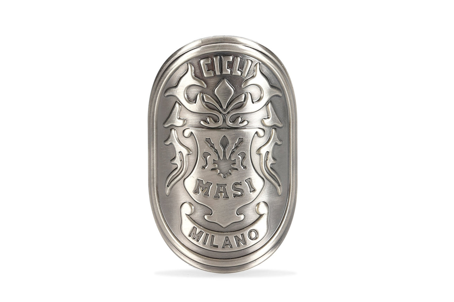 The MASI HEAD BADGE by Masi Bikes is an ornate metallic oval featuring an intricate floral design and the engraved words Cicli Masi Milano. It has an ancient silver finish, set against a white background.