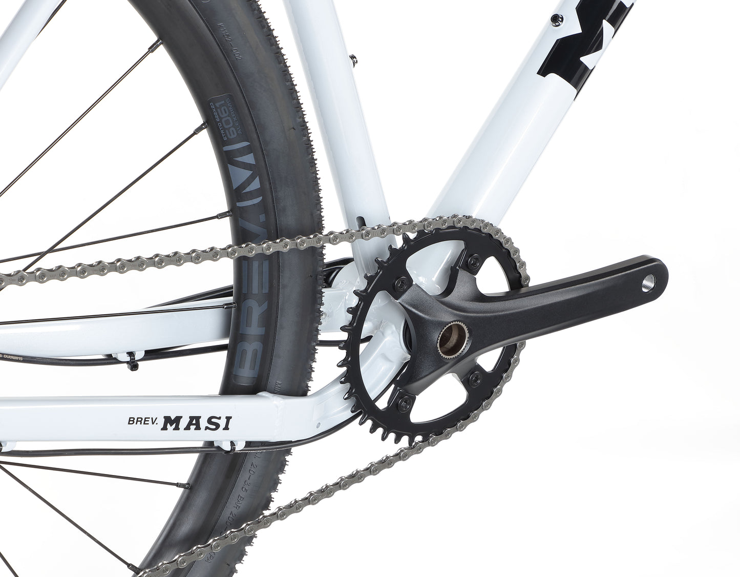 Close-up of a BRUNELLO 3 crankset and chain on a white frame, showcasing the rear wheel and tire branding.