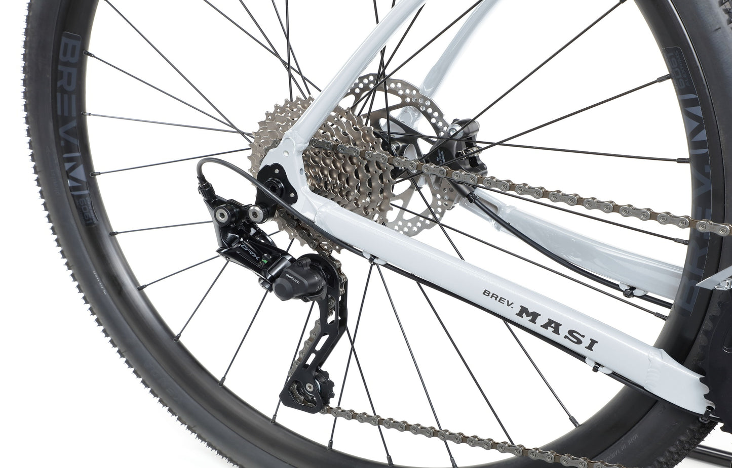 Close-up of BRUNELLO 1s rear wheel, gears, derailleur, and disc brake on a white frame with MASI branding.