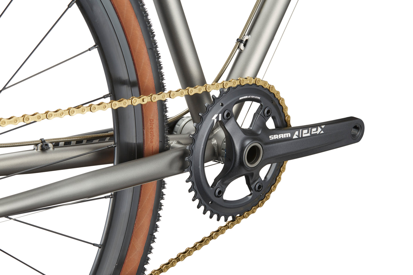 Close-up of the CATALINA 1 drivetrain featuring a SRAM Apex crankset, gold chain, brown sidewall tire, and chromoly steel frame.