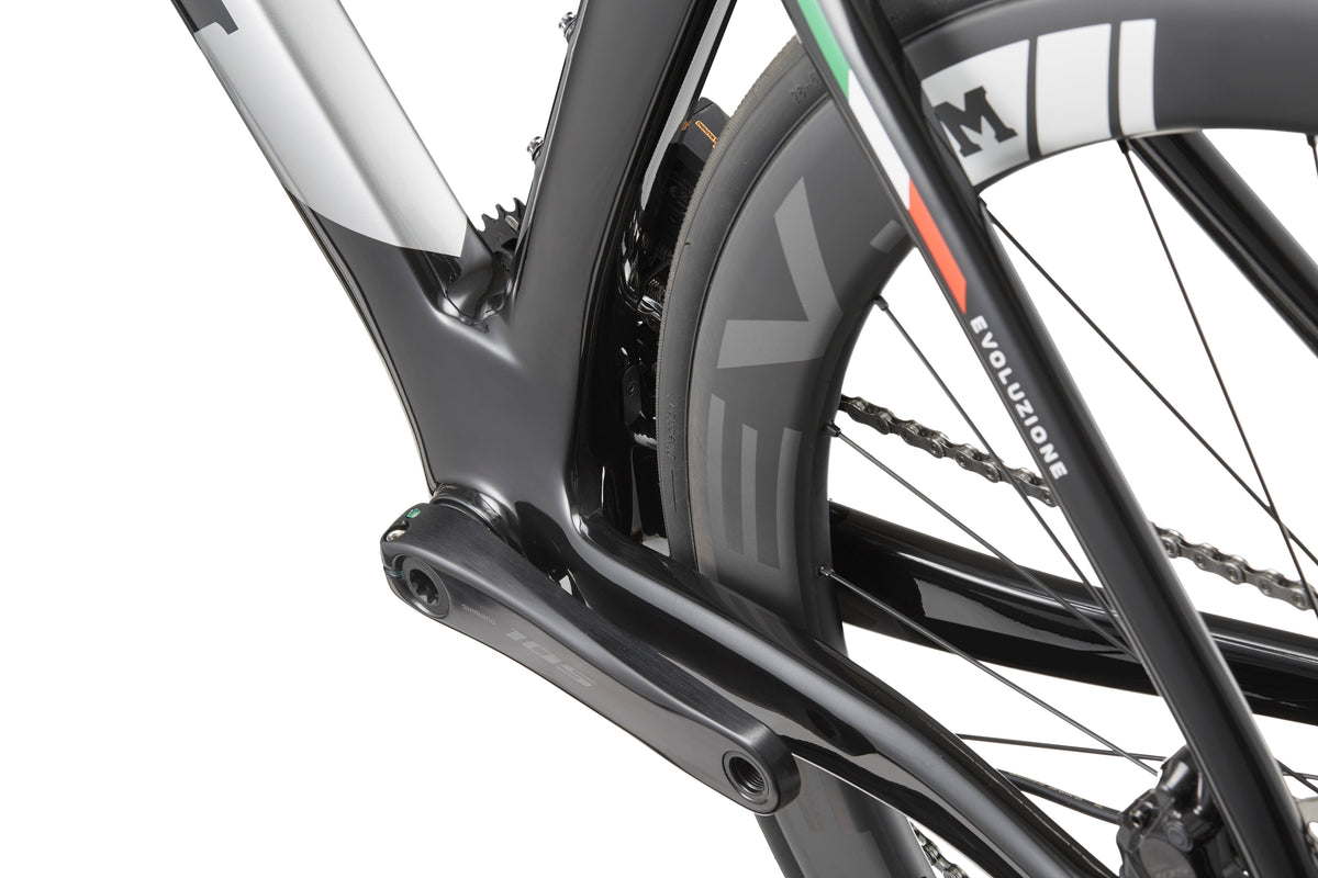 Close-up of an EVOLUZIONE 1 Carbon rear wheel, black frame, and visible chain showcasing its aerodynamic design.