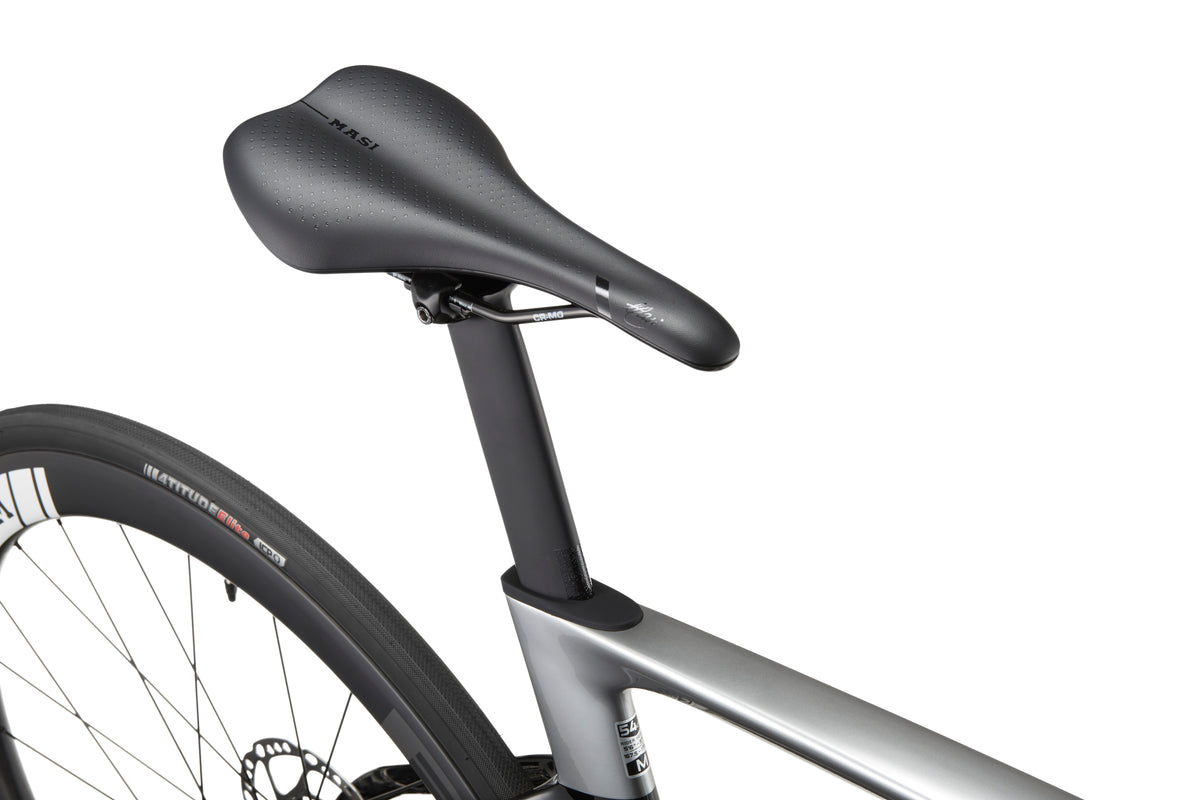 Close-up of a black bicycle saddle and seat post on the sleek EVOLUZIONE 1 Carbon, highlighting its aerodynamic design near the rear tire.