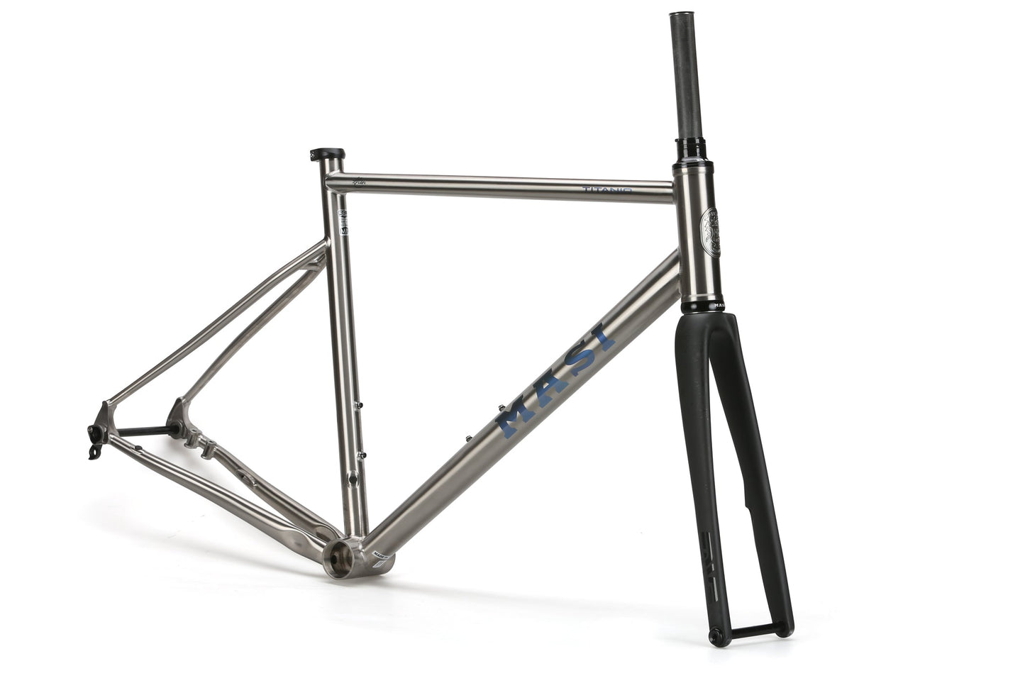 The Masi Bikes TITANIO FRAMESET features a silver titanium race bike frame with MEST on the side and a black fork, set against a white backdrop. Its minimalist design offers versatility with 32c tire clearance.
