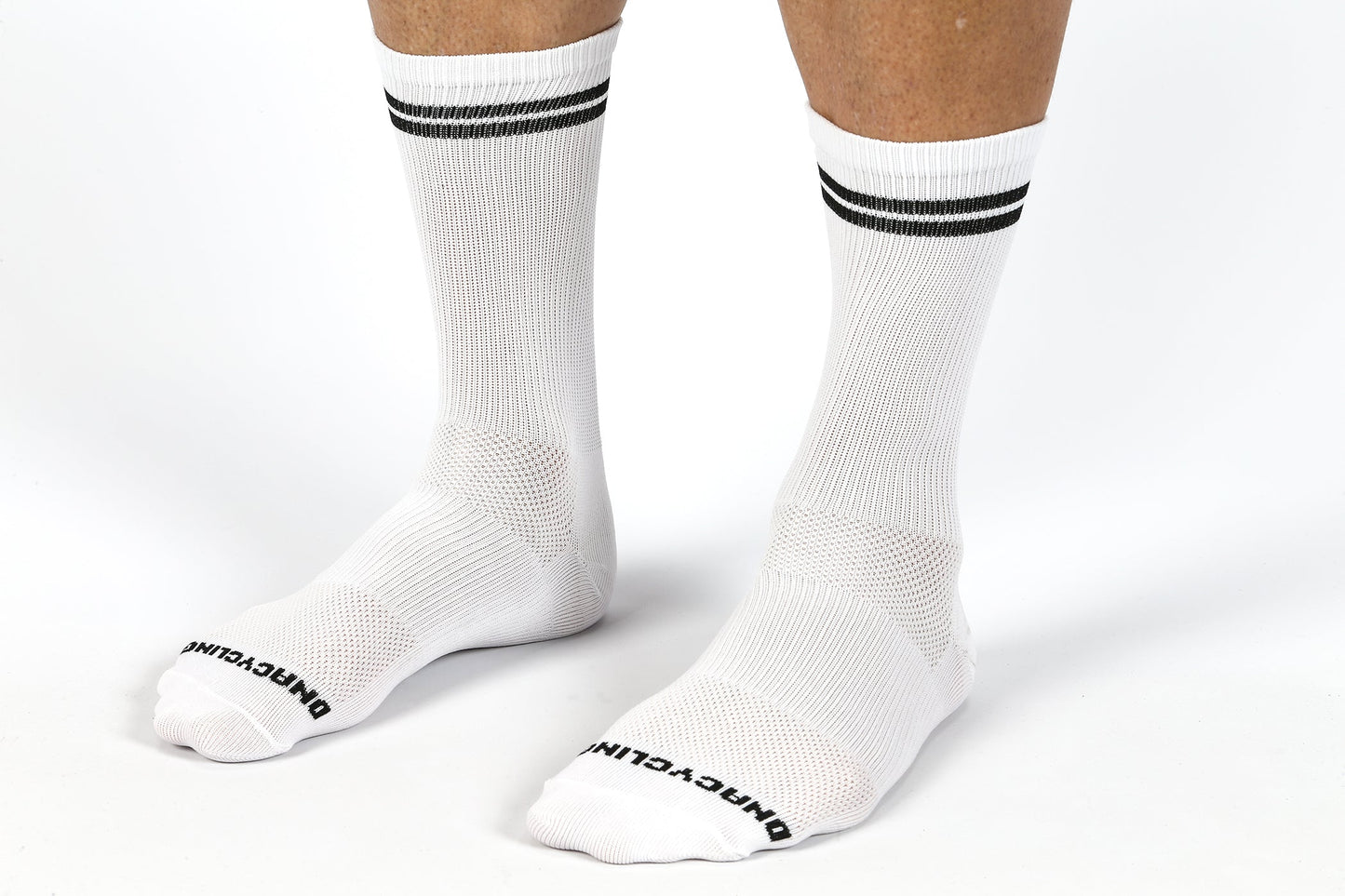 Person wearing MASI DNA CYCLING SOCKS WHITE by Masi Bikes with black double stripes at the top, against a white background. The toes feature UNSWAGLYFE in black. These breathable socks ensure optimal comfort and sweat-wicking performance.