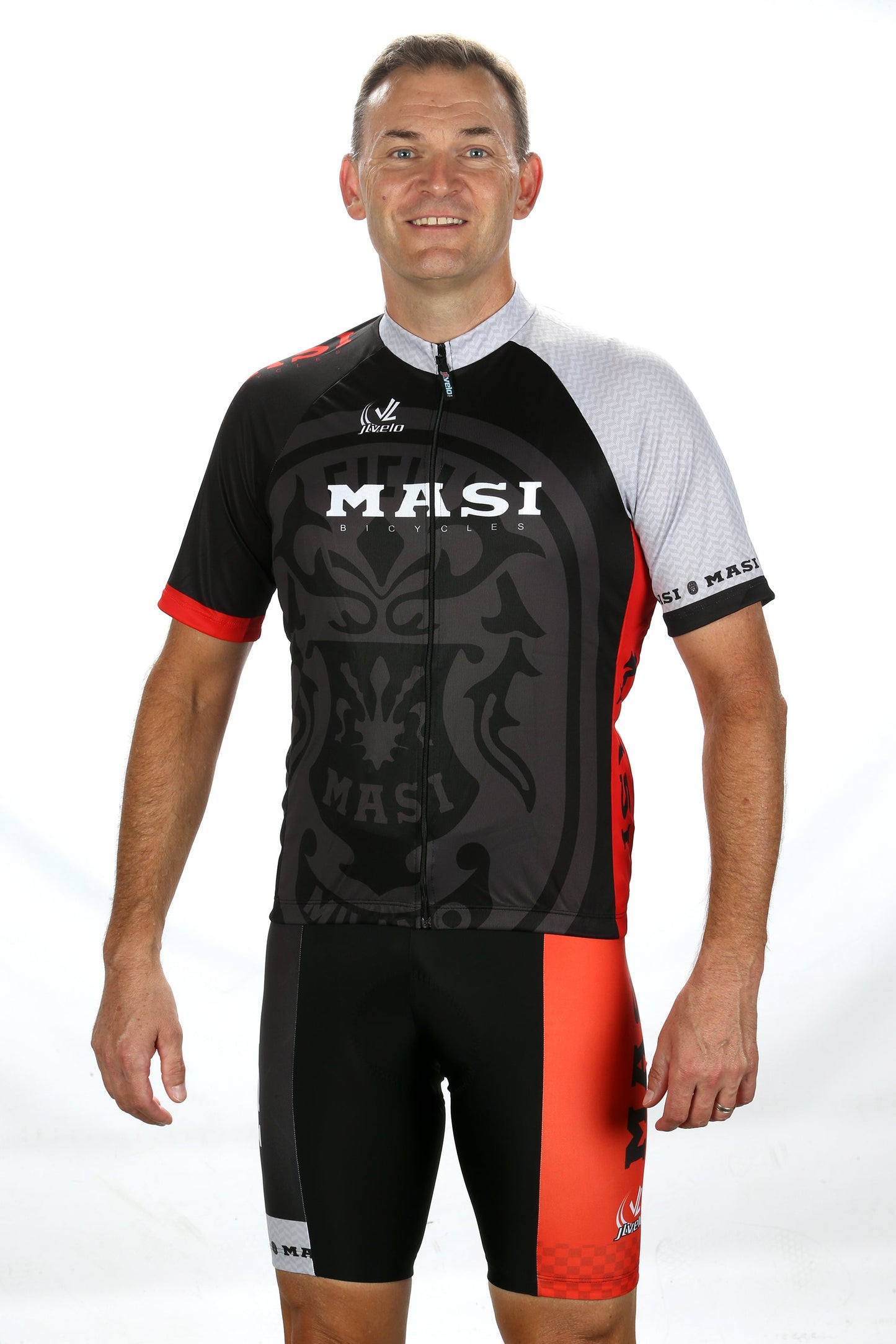 A person wearing the MASI RGB JERSEY by Masi Bikes in black, red, and gray stands against a plain white background.