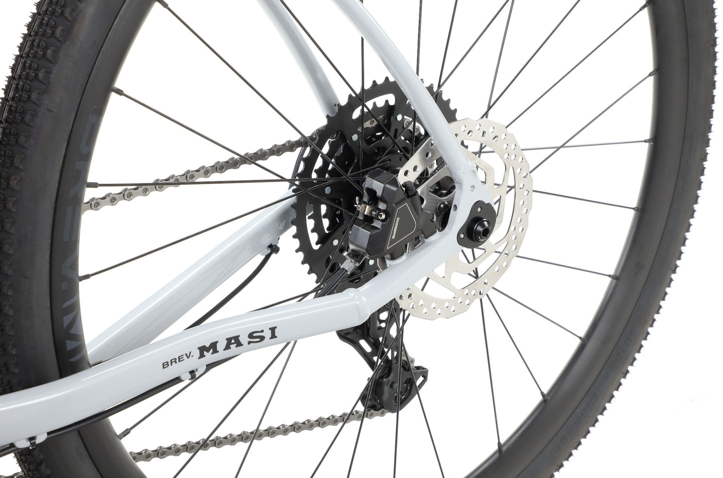 Close-up of the BRUNELLO 3 gravel bike’s rear wheel with disc brake, gears, chain, and BREV. MASI on the alloy frame.