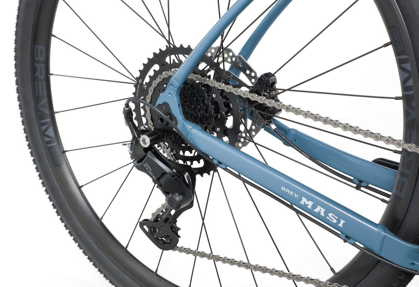 Close-up of BRUNELLO 3s rear wheel, featuring gear cassette, chain, disc brake, and tubeless-ready wheels on white background.