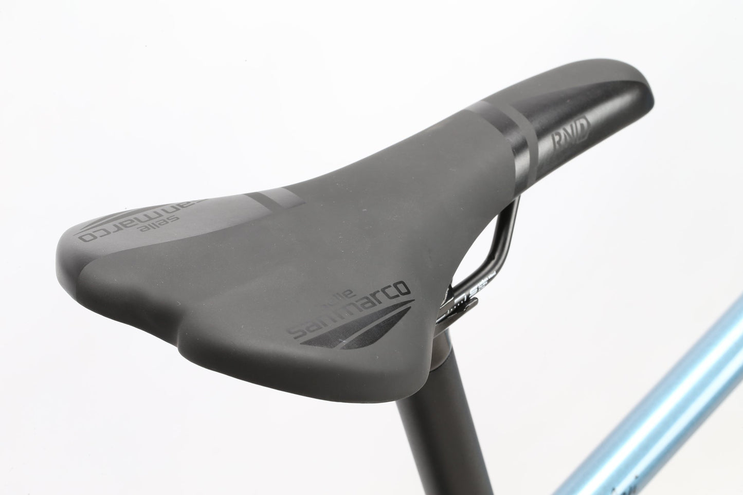 Close-up of a sleek black saddle with Selle San Marco branding on a light blue Masi Bikes touring frame, capturing the essence of adventure. The GIRAMONDO 700c model elegantly stands against a plain white background.