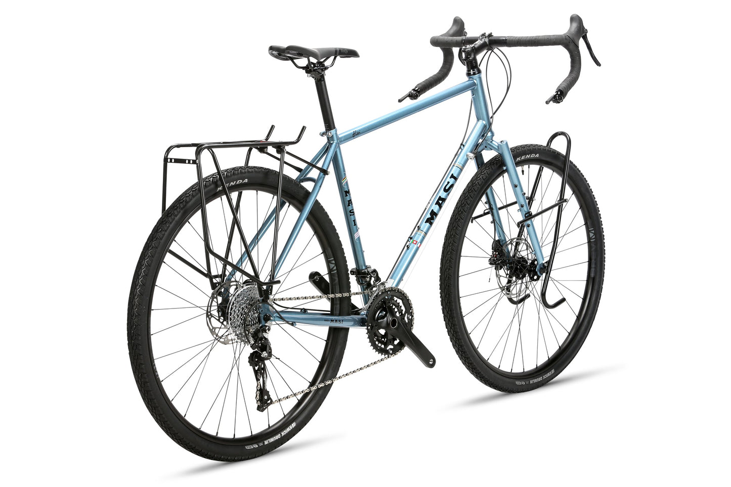 The Masi Bikes GIRAMONDO 700c touring bike features drop handlebars and disc brakes for adventure. With a light blue color, it includes front and rear racks, knobby tires for all terrains, and an angled display highlighting its gears and robust frame—ideal for your next journey.