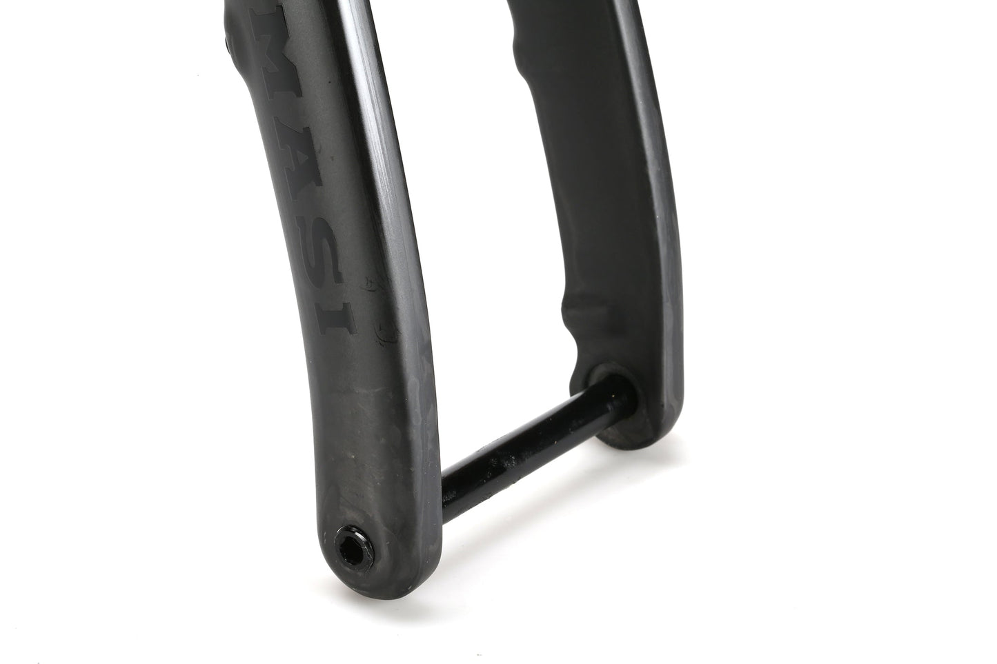 Close-up of titanium bicycle fork dropout with through axle on the Masi Bikes INCANTO Ti FRAMESET. The black fork has a slight sheen, features 3AL/2.5V tubing, and displays part of the brand name MASI. The cylindrical axle is centered on the gravel bikes frame.
