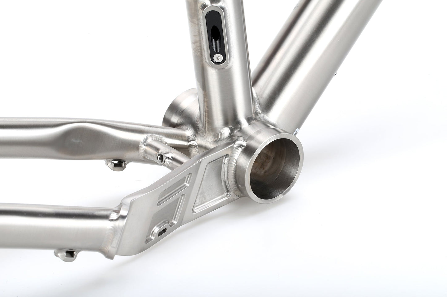 Close-up of the INCANTO Ti FRAMESET by Masi Bikes highlighting meticulous craftsmanship in the titanium 3AL/2.5V tubing, with a focus on its sleek bottom bracket design, all set against a white background.