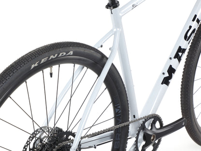 Close-up of the BRUNELLO 3s white frame, featuring the rear wheel with a Kenda tire and visible chainring and crankset.