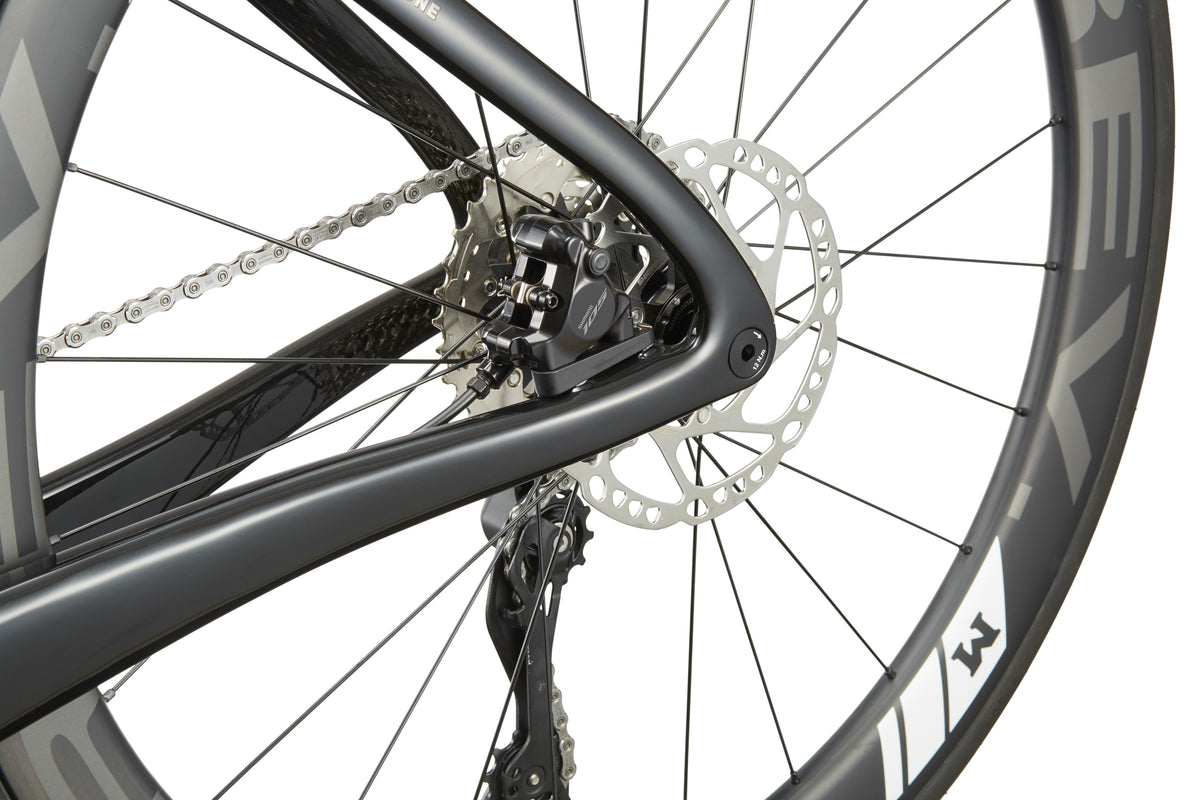Close-up of an EVOLUZIONE 1 rear wheel highlighting its sleek frame, chain, and disc brake, exemplifying modern aerodynamic design.