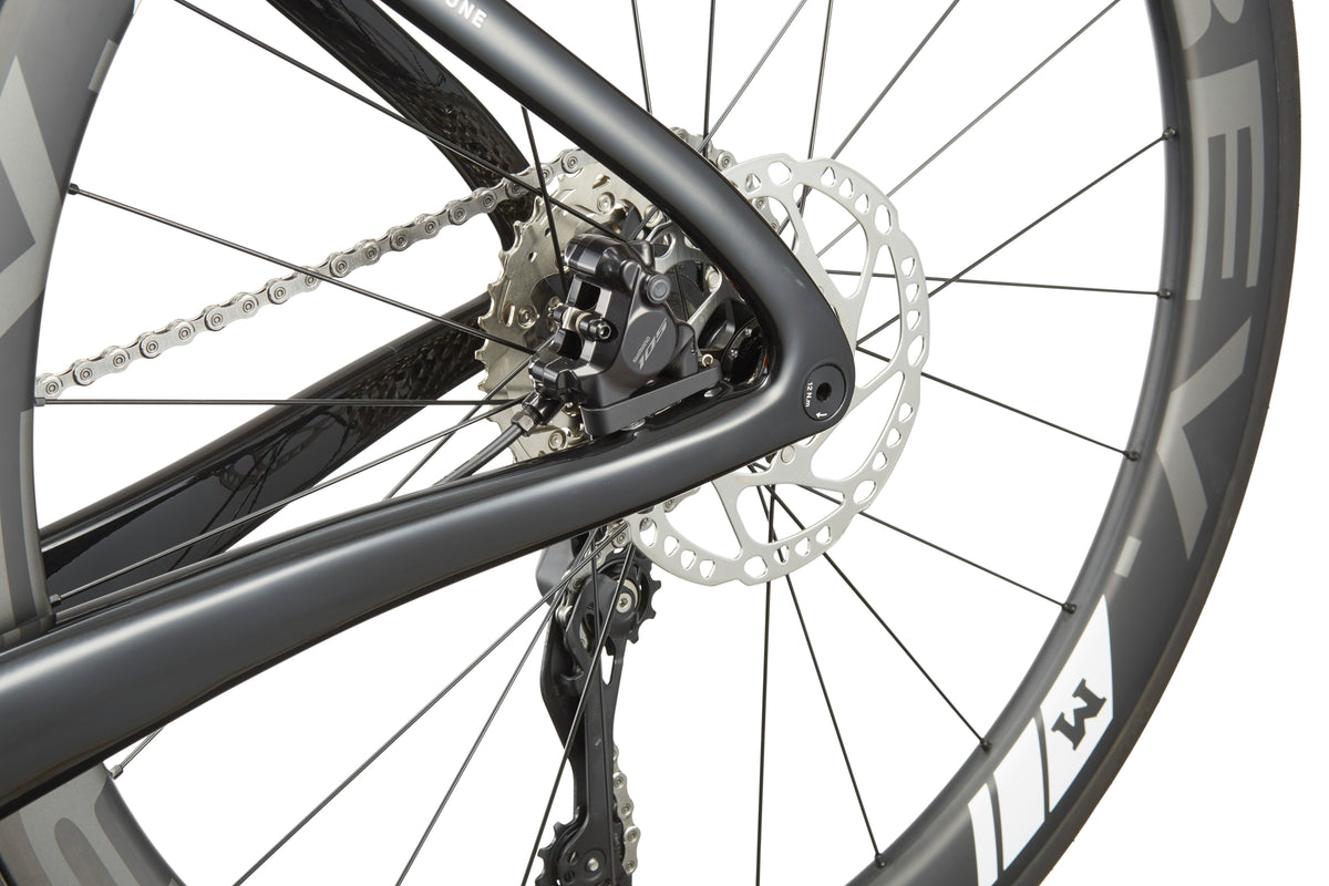 Close-up of the EVOLUZIONE 1, a sleek carbon bike wheel with disc brake, chain, and aerodynamic design for high performance.