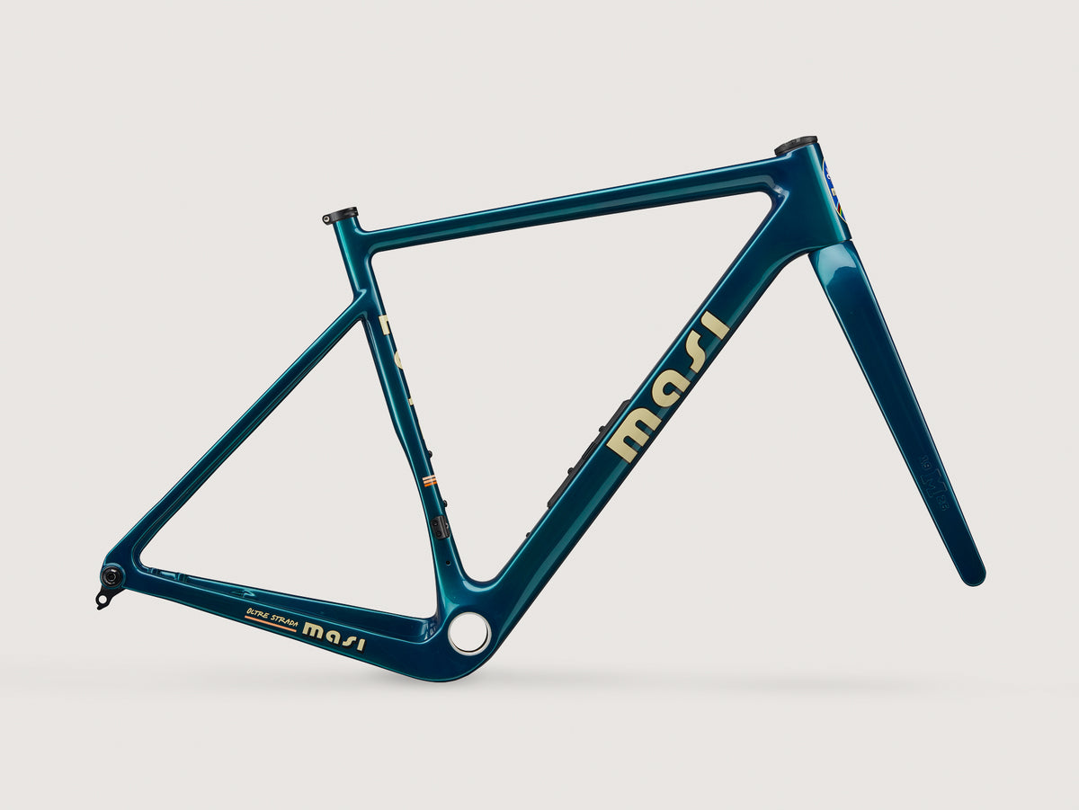 A teal Oltre Strada gravel frame with gold lettering on white background; ample tire clearance. Frame only—no wheels or components.