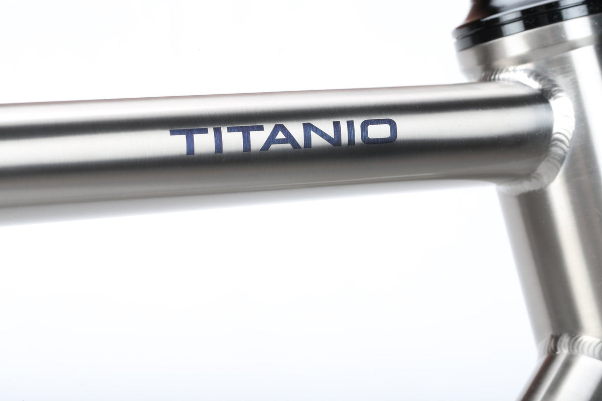 Close-up of a premium titanium TITANIO FRAME with the product name printed on the top tube.