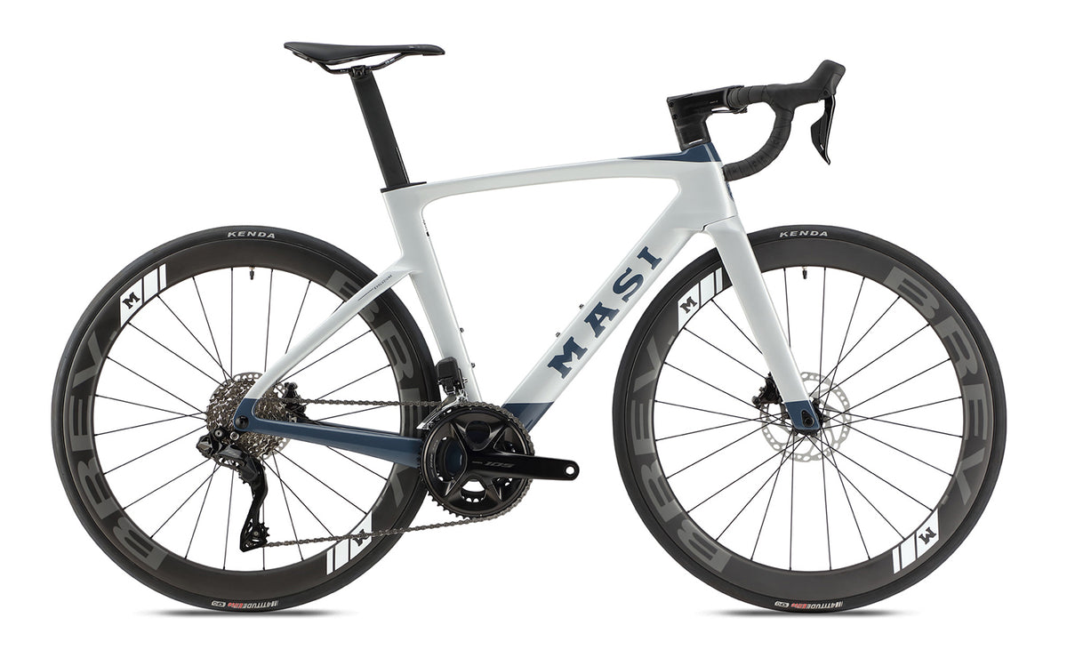 The Masi Bikes Evoluzione 1 is a sleek, modern road bike with a white and blue frame. It features aerodynamic design, disk brakes, and deep-section wheels. Masi Bikes is proudly displayed on the frame.